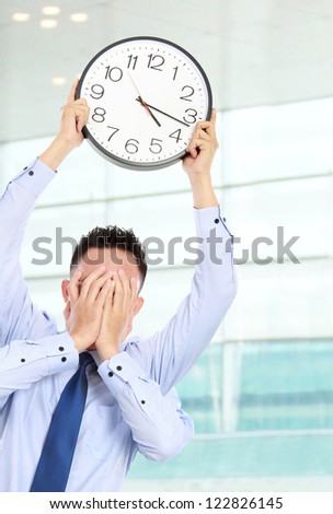 deadline concept of businessman with many hands holding clock and covering face in the office