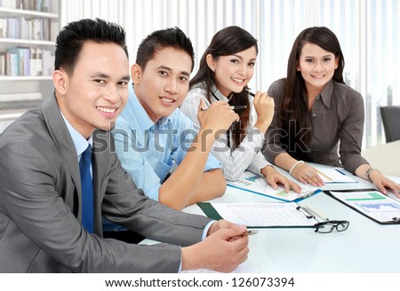 Portrait of group executives meeting around a table with many paperwork