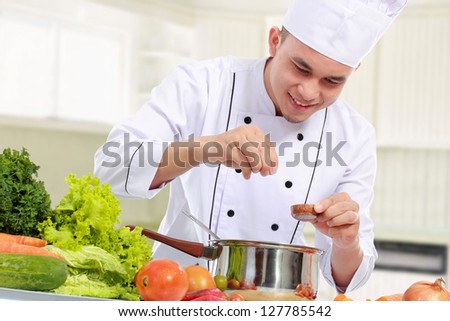 happy smiling male chef put some ingredient in the pan