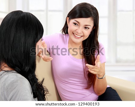 Two women friends chatting on the couch at home