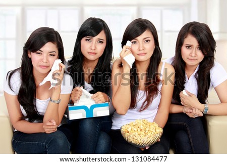 Group of teenager girl sitting on couch watching movie with sad expressions