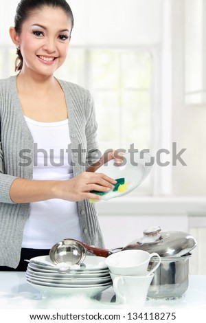 Happy Young asian Woman Washing Dishes in the kitchen