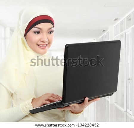 young asian muslim woman in head scarf using laptop computer in the office