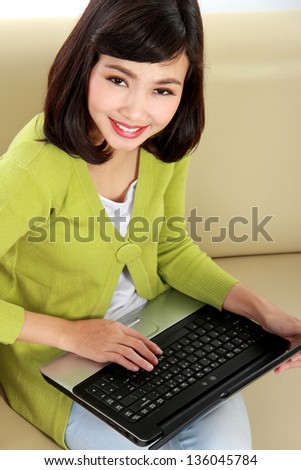 Beautiful smiling woman with laptop sitting on the couch