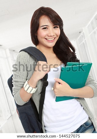 portrait of smiling student with bag and holding notebooks