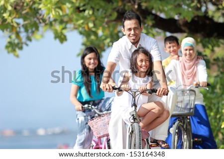 Portrait of happy muslim family with kids enjoy riding bicycle outdoor in the beach