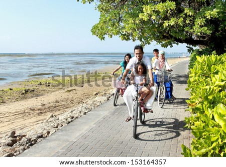 Happy asian family riding bikes in the beautiful morning at the beach. Outdoor portrait
