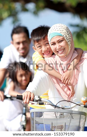 Portrait of happy muslim family riding bikes together in beautiful sunny day