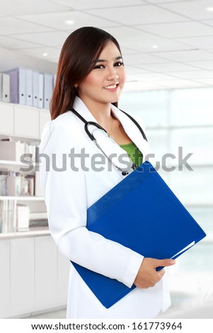 Attractive female doctor in lab coat holding clipboard at hospital