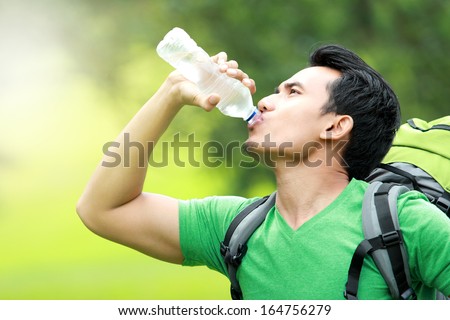 hiking concept. thirsty man having a break drinking a bottle of water
