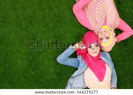 Portrait Of Two Beautiful Happy Muslim Woman Smiling Lying On Grass With Copy Space