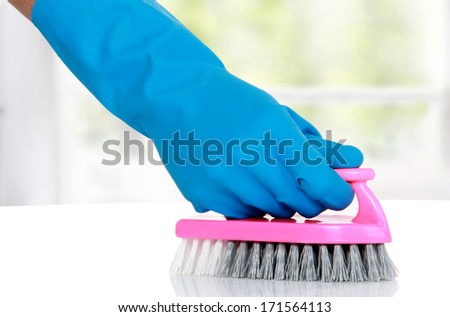 hand with glove using cleaning brush to clean up the floor