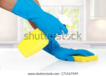 hand with glove using cleaning sponge to clean up the table