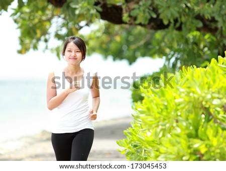 Smiling Sporty female runner jogging on beach.