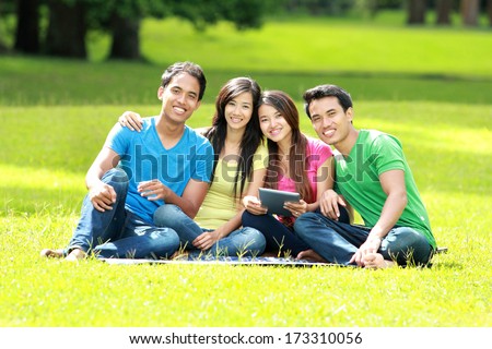 Group of young student using tablet pc together in the park
