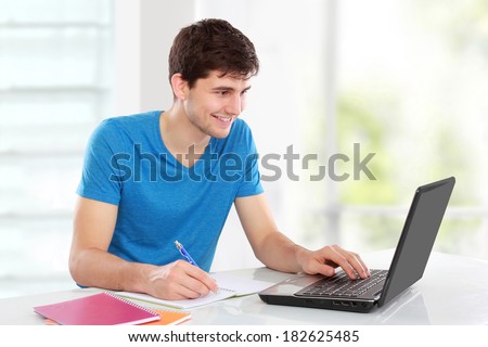 Handsome college student using his laptop computer in the campus