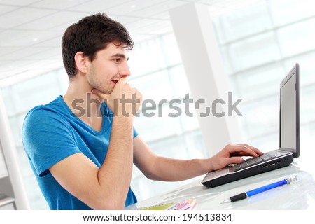 Handsome college student using his laptop computer in the campus
