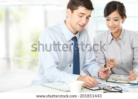 Image of two young business people at the meeting in the office using credit card