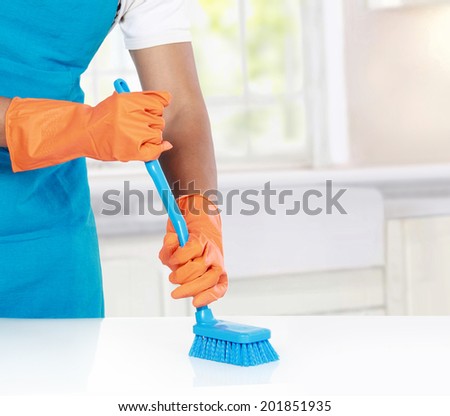 hand with glove using cleaning brush to clean up the floor or table