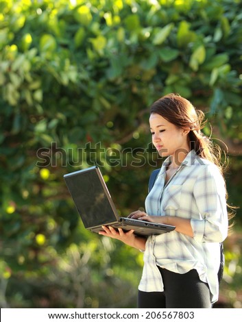Young student doing homework with laptop in the park