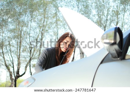 portrait of young woman try to find a problem of her car engine