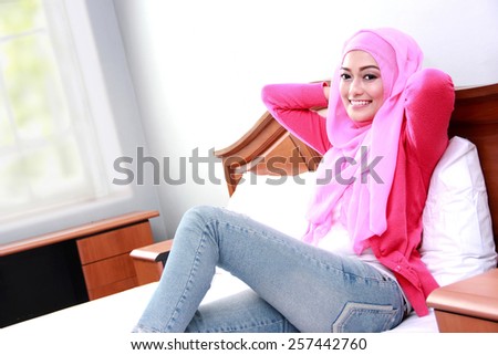 side view portrait of young muslim woman relaxing body on bed
