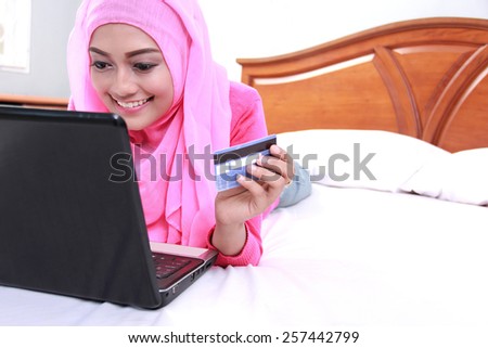 portrait of young muslim woman working on laptop and make a payment using credit card