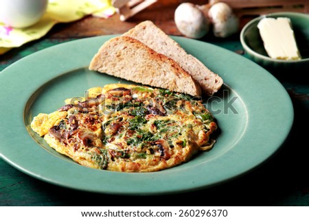 portrait of healthy breakfast spinach mushroom omelete served with toast and butter
