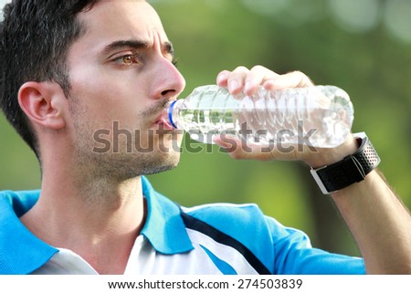 close up portrait of sporty male runner drinking mineral water at the break after tired running