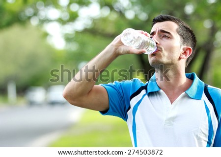 portrait of sporty male runner drinking mineral water at the break after running