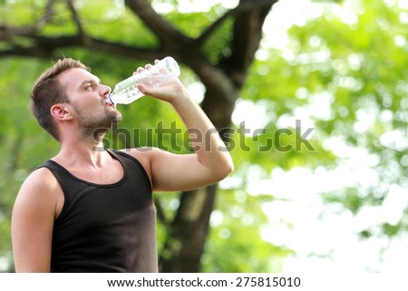 portrait of male runner drinking mineral water at the break after running with copy space