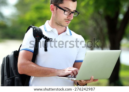 handsome college student with backpack surfing the internet using a laptop