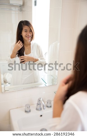 A portrait of an asian woman posing infront of a mirror, smiling happily