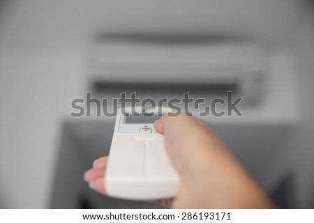 A portrait of a hand using a remote to activating air conditioning machine