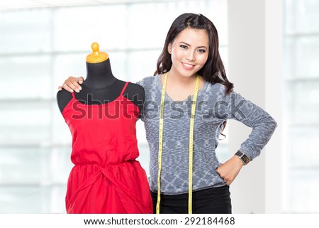A portrait of a young asian designer woman with mannequin or dummy posing smiling, hold a scissors,  look at the camera