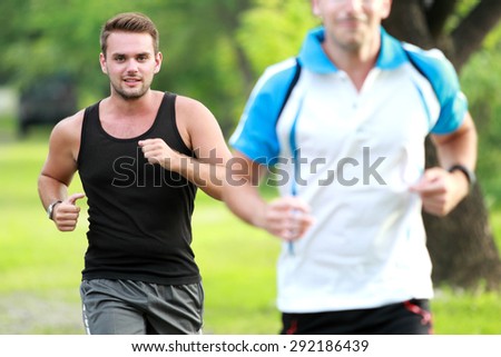 portrait of two young sport man jogging together at roadside
