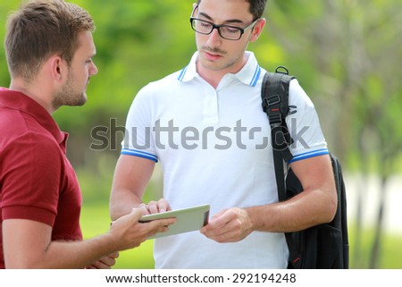 portrait of a college student explaining a task to his friend at college park