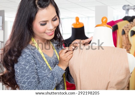 A portrait of a fashion designer or Tailor working on a design or draft, fix it with sewing needle