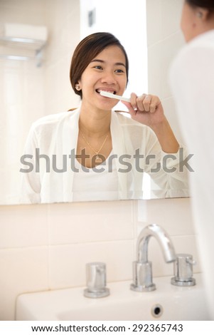 A portrait of an Asian young woman tooth brushing her teeth happily