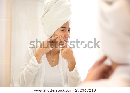 A portrait of a Young asian woman pressing her face, trying to remove acne