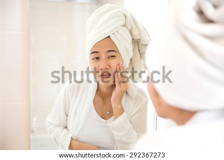 A portrait of a Young asian woman pressing her face, trying remove acne