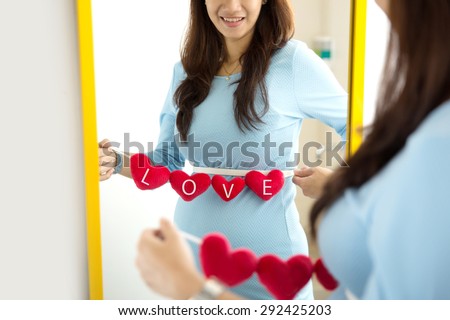 A portrait of Asian pregnant woman with heart shape accessories on her tummy