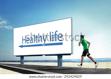 A portrait of a Asian young man running on beach, Sport healthy life concept with a big billboard