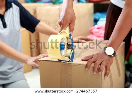 portrait of worker using duck tape for packing product into a box at textile factory