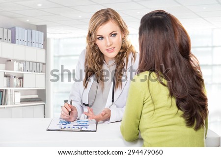 A portrait of a Doctor with female patient. Friendly, Happy Doctor with Stethoscope Giving Advice to Patient in Clinic