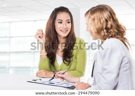 A portrait of a Doctor with female patient. Friendly, Happy Doctor with Stethoscope Giving Advice to Patient in Clinic