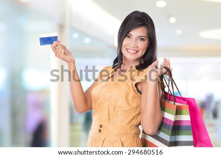 A portrait of happy Asian woman holding shopping bags and credit card