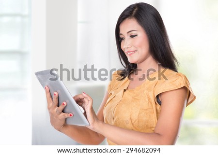 A portrait of an asian woman holding a digital touch screen tablet computer