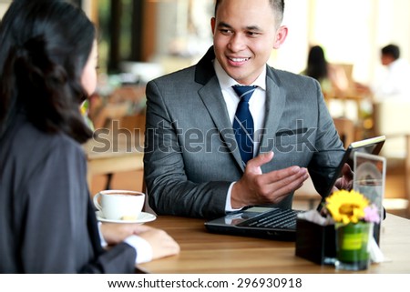portrait of two businesss people talking about planning work at cafe