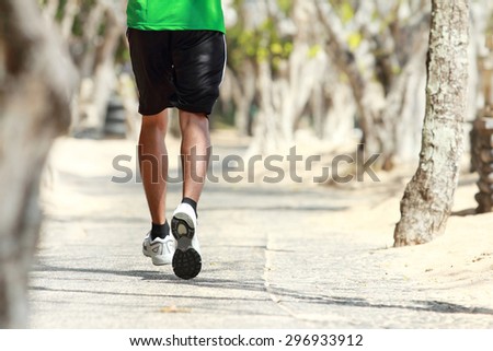 portrait of man\'s foot running on the alley with trees alongside, focused on foot
